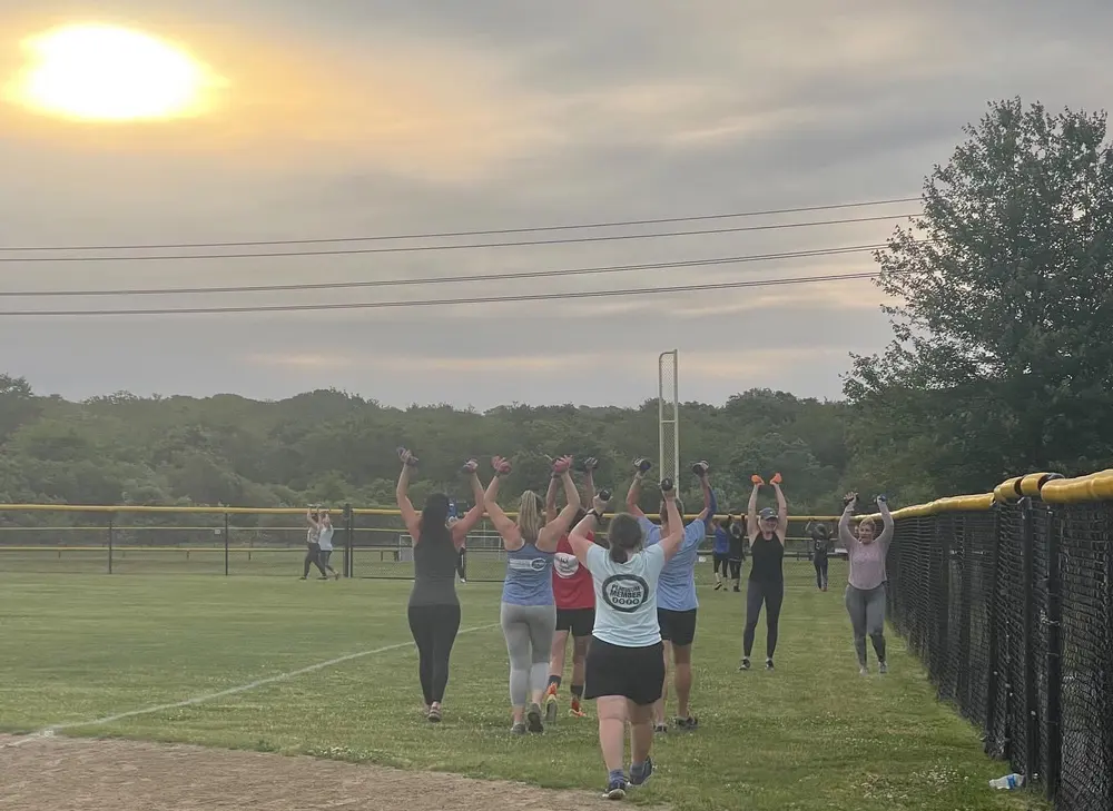 SC Boot Camp members walking across the field with dumbbells at Broadrock Athletic Fields in South Kingstown, Rhode Island