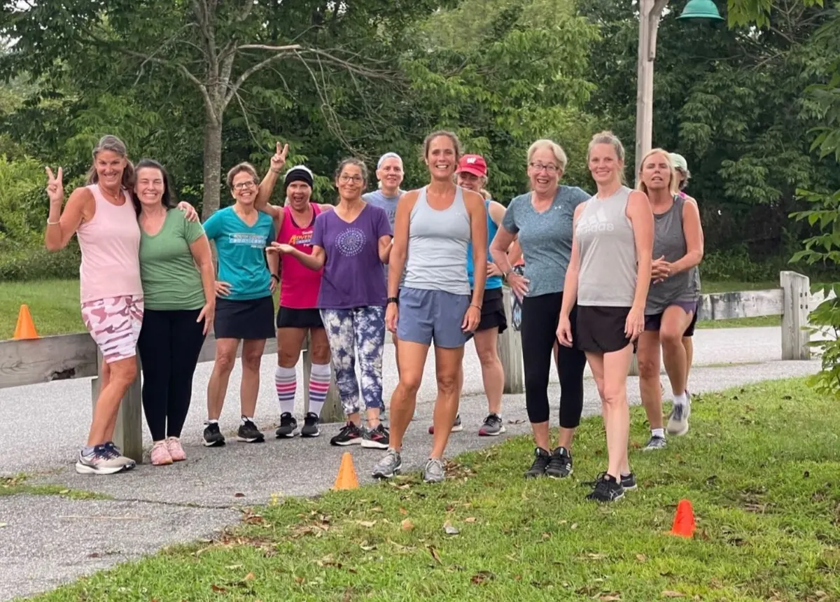 SC Boot Camp members smiling together on a wooded path during a morning session